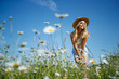 © nuzza11 - Woman in a field with flowers. Beautiful girl in a field with daisies.