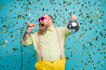 Portrait of his he nice attractive cheerful bearded mature guy holding in hand disco ball having fun singing karaoke isolated over bright vivid shine vibrant blue color background