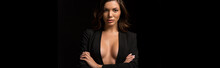 Panoramic Shot Of Confident, Seductive Girl In Unbuttoned Blazer Posing With Crossed Arms Isolated On Black