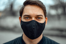 Portrait Man In Medical Mask. Young Man Stands On Light Background And Looking At Camera.