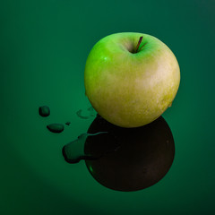 Wall Mural - Wet green apple on wet dark green background.