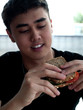 © Lucky Dragon - junger Mann isst ein Vollkornhaferbrot mit Tomaten-Gurken-Sandwich