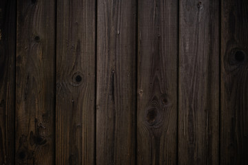 The texture of the Wooden wall a dark brown color with vertical boards in rustic style