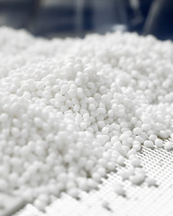 Wall Mural - Vertical closeup of a white plastic polymer granule in a laboratory on a blue background.