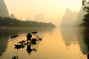 Silhouette of Fishing Men and His Cormorants on Li River at Sunrise, Guilin, China. The Li River or Lijiang is a river in Guangxi Zhuang Autonomous Region, China.