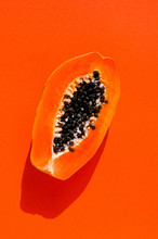 Fresh Papaya Exotic Tropical Fruit On Orange Background. Sun Day Light Illumination. Minimalistic Summer Flat Lay Wallpaper. Creative Food Concept. Copy Space Template. Bold Colors