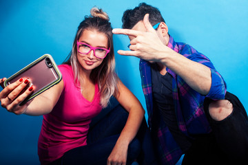 happy couple together posing cheerful on blue background wearing glasses, guy and girl students together friends