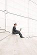 © PeskyMonkey - Businessman sitting outdoors on minimalist marble steps using his laptop computer