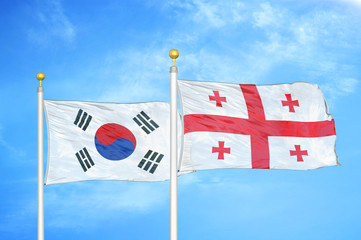 South Korea and Georgia two flags on flagpoles and blue cloudy sky