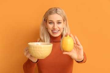 Poster - Beautiful young woman with tea and lemon on color background