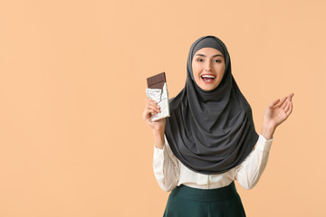 Sticker - Beautiful Muslim woman eating tasty chocolate on color background