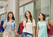 © Denys Kurbatov - Three young happy women with shopping bags walking in shopping mall