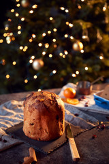 Traditional Christmas Panettone On Table Set For Festive Meal With Tree Lights In Background