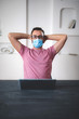 © astrosystem - Freelancer with medical protective mask working from home in the days of pandemic and social distancing.