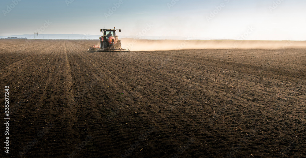 Tractor is preparing the land at dusk - obrazy, fototapety, plakaty 