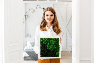 Girl of European appearance in a modern interior, with long blonde hair, decorating the house, forms of glass and plants, stones and moss, designer, freelance