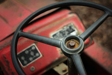 A Broken Red Tractor In The Farmland, The Steering Wheel Is Still Completely Placed In Front Of The Driver's Seat