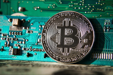 Wall Mural - silver bitcoin coin in front of computer motherboard, cryptocurrency mining and investing concept
