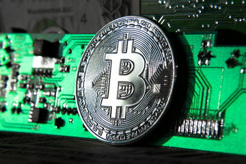 Wall Mural - silver bitcoin coin in front of computer motherboard, cryptocurrency mining and investing concept