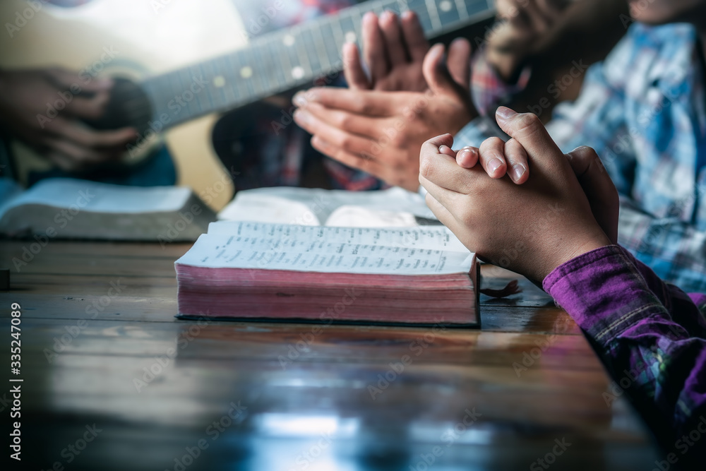 Group of christian sitting praying and worship God by playing guitar and sing a song together in home, christian worship meeting concept. - obrazy, fototapety, plakaty 