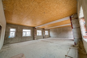 Canvas Print - Unfinished apartment or house big loft room under reconstruction. Plywood ceiling, plastered walls, window openings, cement floor. Construction and renovation concept.