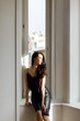 © cmirnovalexander - Brunette girl in a leather skirt and a wine blouse sits near a window on a windowsill in the sun