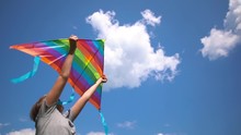 Closeup View Video Of Two Kids Hands Holding Bright Colorful Kite Overhead Isolated At Bright Clear Blue Sky Background.