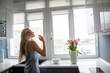 © Вероника Зеленина - Beautiful blond housewife woman start to cooking in the kitchen. Female inhales the smell of flowers and look to the window