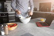 Mężczyzna w kuchni miesza sałatkę w misce na stole kuchenym.