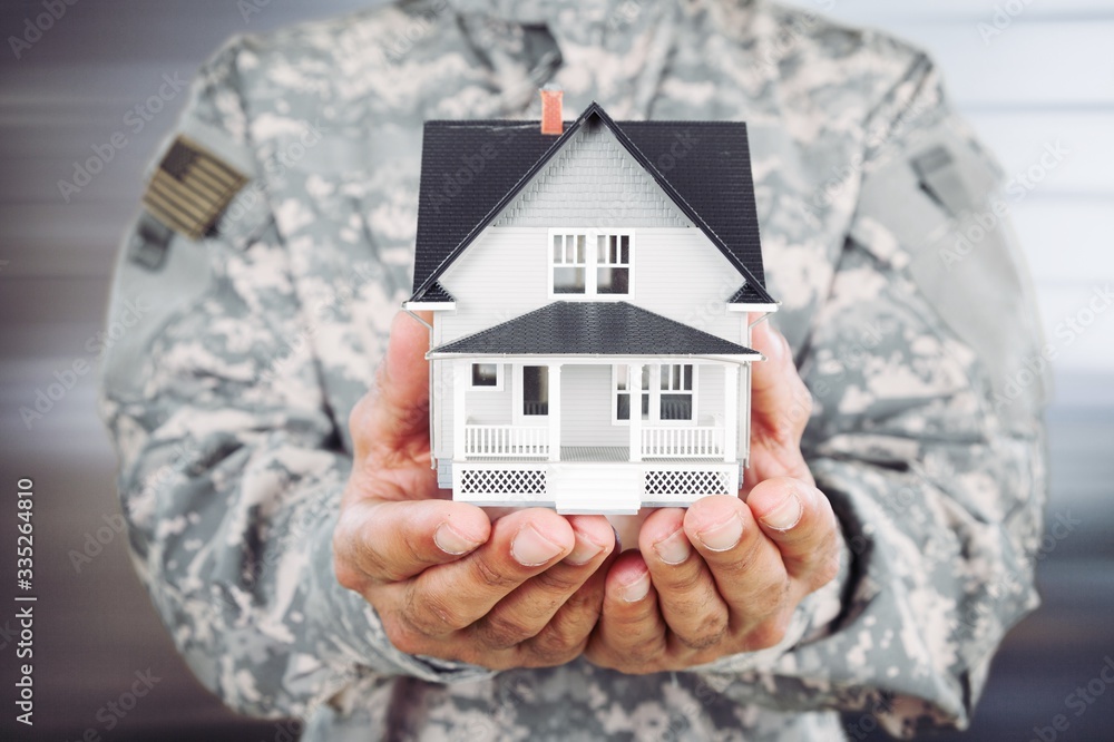 Soldier man holding a model of the house - obrazy, fototapety, plakaty 