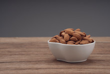 Almonds In White Porcelain Bowl On Wooden Table
