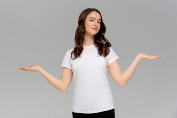 Close up portrait of bored young woman in white t-shirt throw their hands up, staring with indifferent, watching tv at home during quarantine, dont know what do, feel sad, isolated on gray background