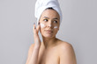 © Mountains Hunter - Beauty portrait of woman in white towel on head applies cream to the face. Skincare cleansing eco organic cosmetic spa relax concept.