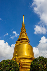 Beautiful golden stupa at the Thai temple in Bangkok with blue sky and white cloud background, Thailand.