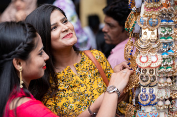 Two young girls are trying necklace and other jewelry in native accessories shop in India. Shopping for Indian festival or wedding .