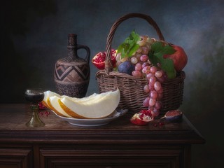 Still life with basket of fruits and melon slices