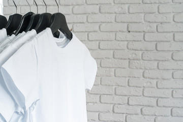 Poster - White t-shirt hanging on hanger against brick wall, copy space