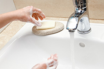 A Hands with soap are washed under the tap with water. Clean from infection and dirt and virus. At home or in the hospital ablution office.