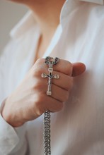 Closeup Shot Of A Religious Male Holding A Silver Necklace With A Cross Pendant