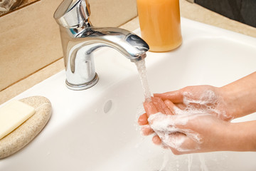 Hands with soap are washed under the tap with water. Clean from infection and dirt and virus.