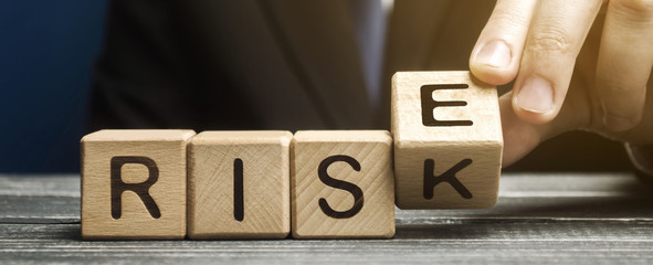 businessman changes wooden blocks with the words risk and rise. business risk management and growth 