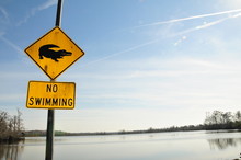 No Swimming Sign By Lake Against Sky