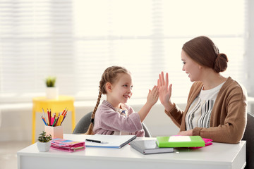 Canvas Print - Mother and daughter doing homework together at table indoors