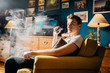 © eldarnurkovic - Parent use of e-cigarettes in the home.Young man inhaling of a vapor with electronic cigarette.Vape flavor liquid chemicals.Smoking and vaping negative health effects.Smoking habit,nicotine addiction.