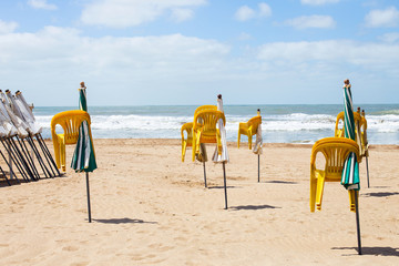 yellow chairs hang on closed beach umbrellas on a deserted beach by the ocean