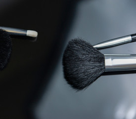 make up brushes lying on black glass table. photo with selectiv focus, low key photo