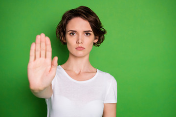 Photo of beautiful serious lady raise hand showing negative reaction say no stop killing animals pollution environment volunteer wear white t-shirt isolated green color background