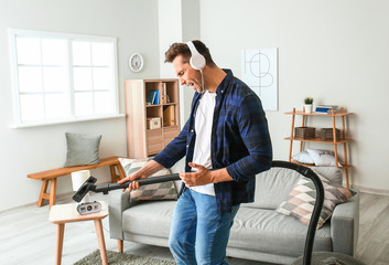 Wall Mural - Cool young man dancing and singing while cleaning his flat