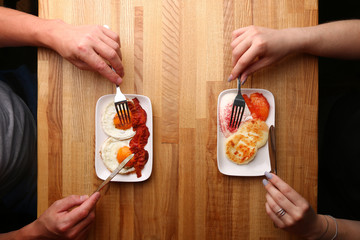 couple have breakfast on wood table cheese pancake with sour cream and fried egg with bacon top view