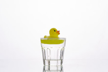 Yellow Rubber Duck Falls Into A Glass On A White Background